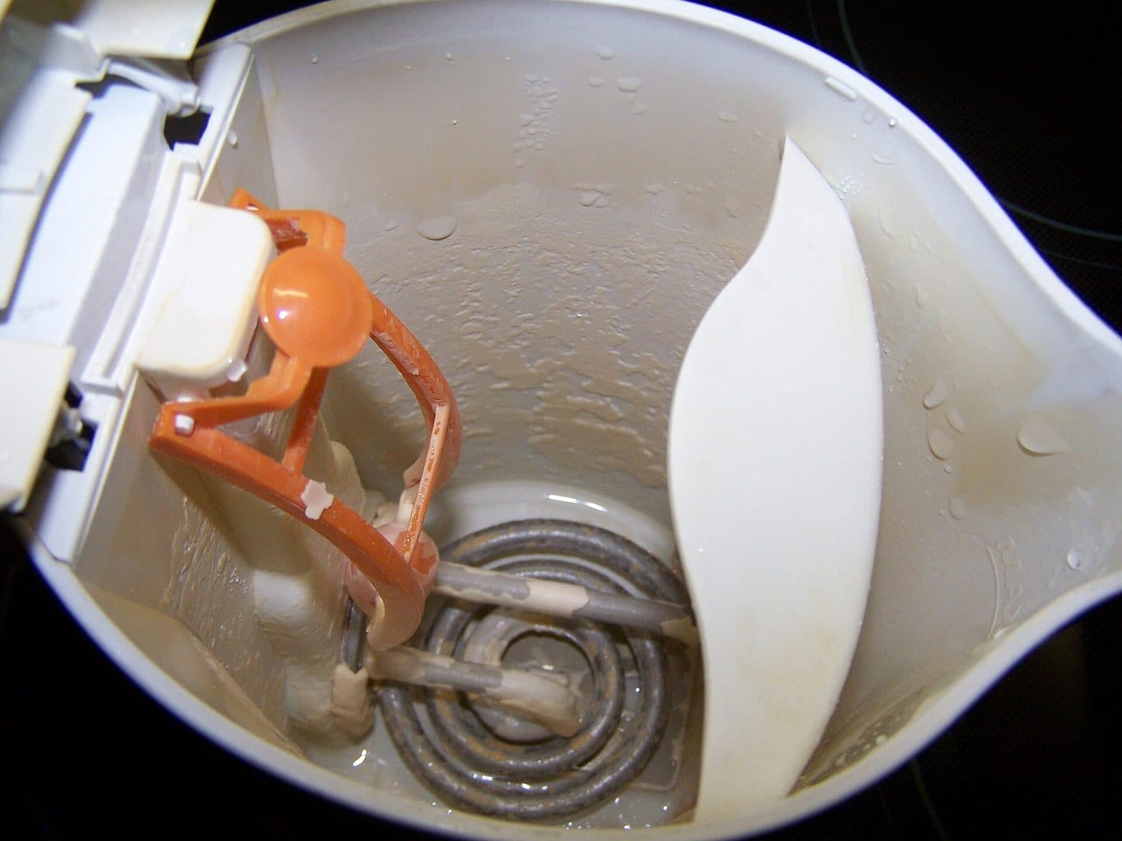 Inside of an electric kettle with limescale on the heating coil and walls